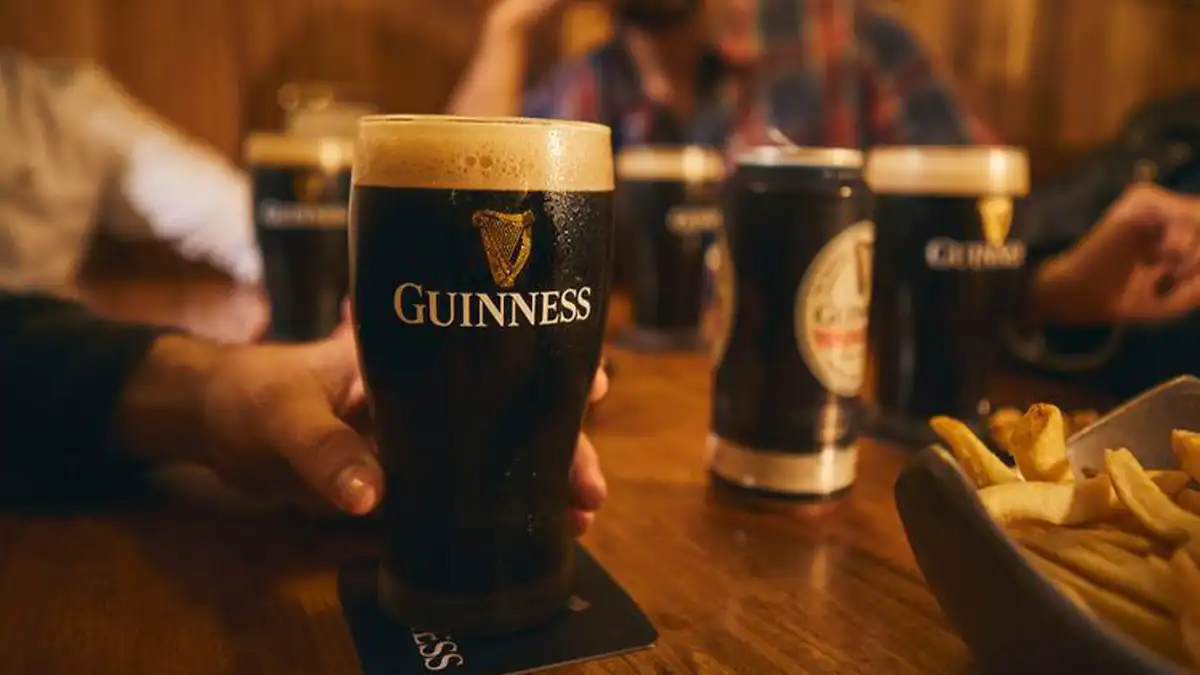 cerveza Guinness sobre mesa de amigos