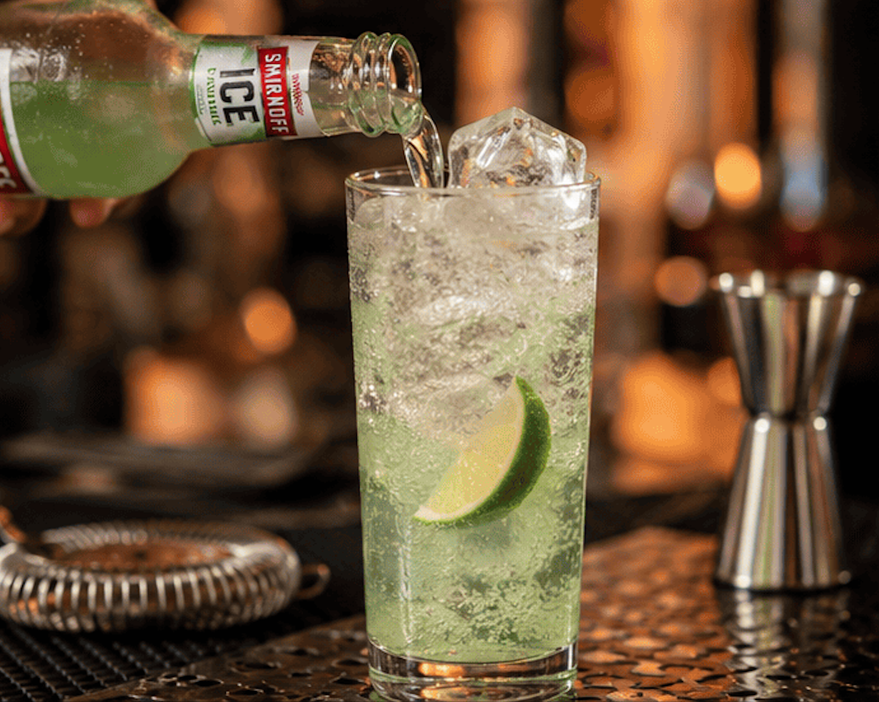 Smirnoff Ice sirviéndose en un vaso largo con hielo y rodaja de lima