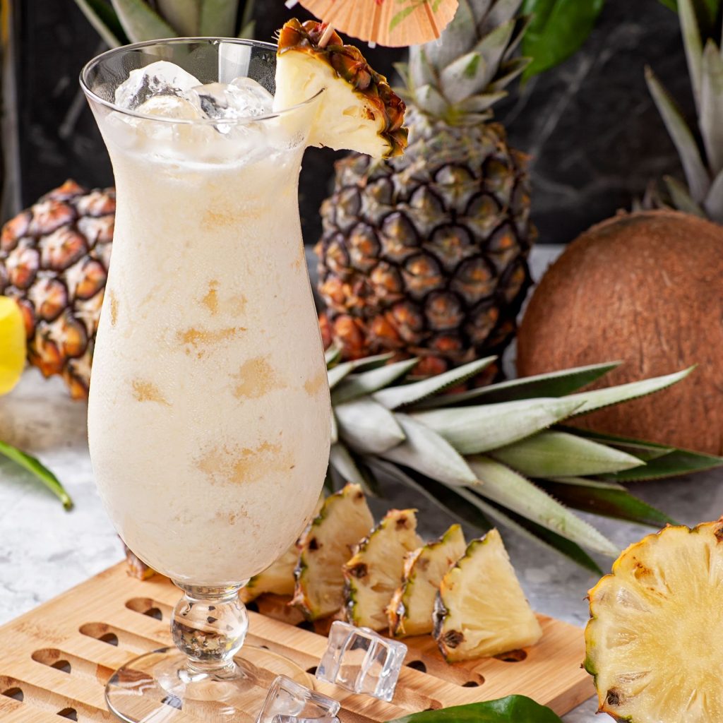 Cóctel de Malibu con piña colada servido en vaso con hielo en una terraza de verano