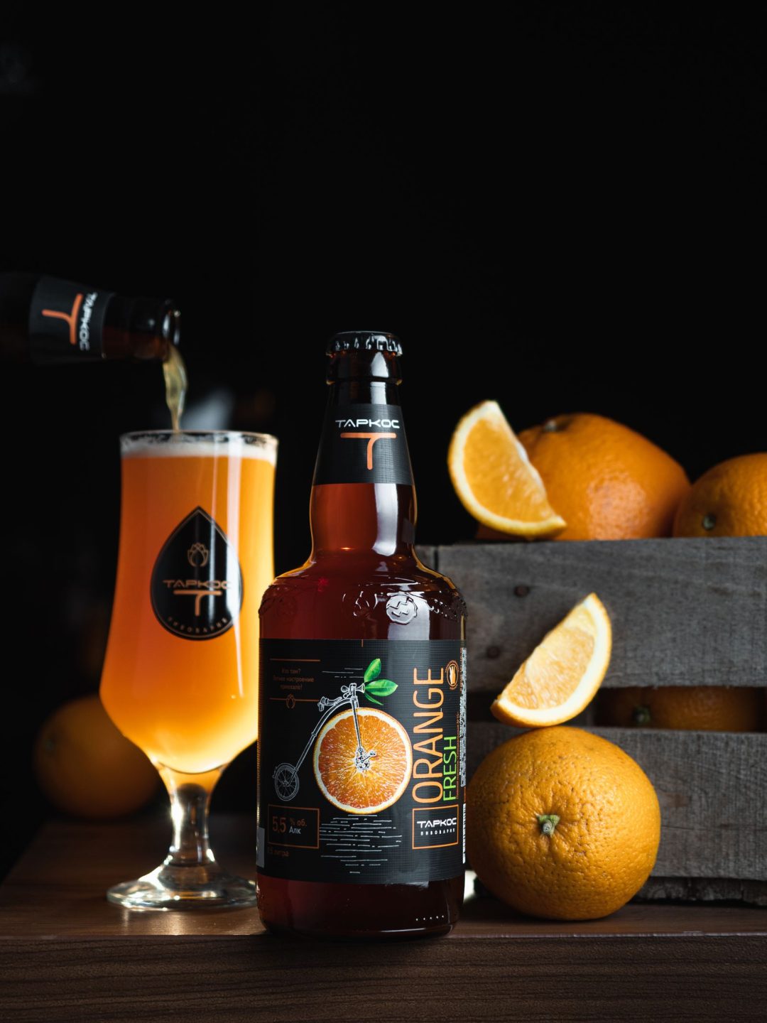 Botella de cerveza junto a naranjas frescas