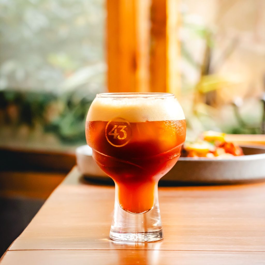 Vaso de cerveza artesanal en copa tulipa sobre una barra