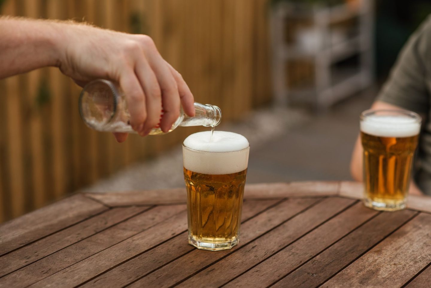 Cerveza servida en vaso con espuma sobre mesa de terraza